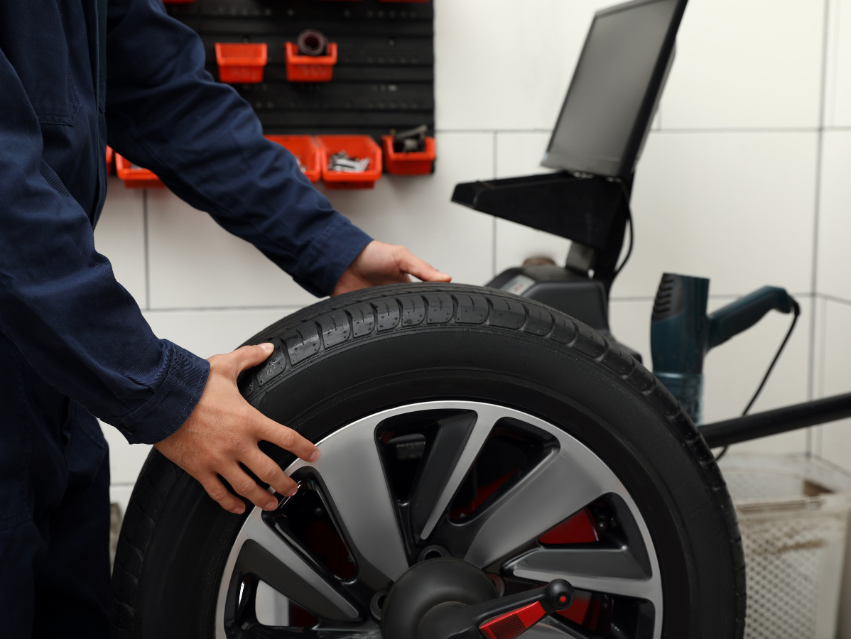 Mechanic balancing a car tire on a machine in a workshop.
