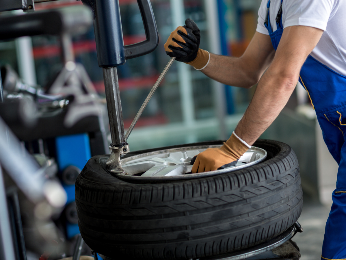 Mechanic using a tire machine to remove a tire from a rim.