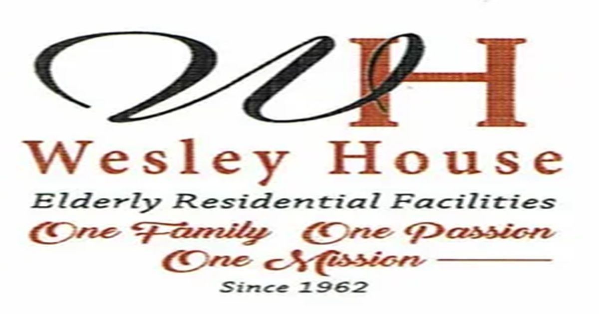 A nurse shows a tablet to an older couple in a bright room with a wheelchair and chairs.