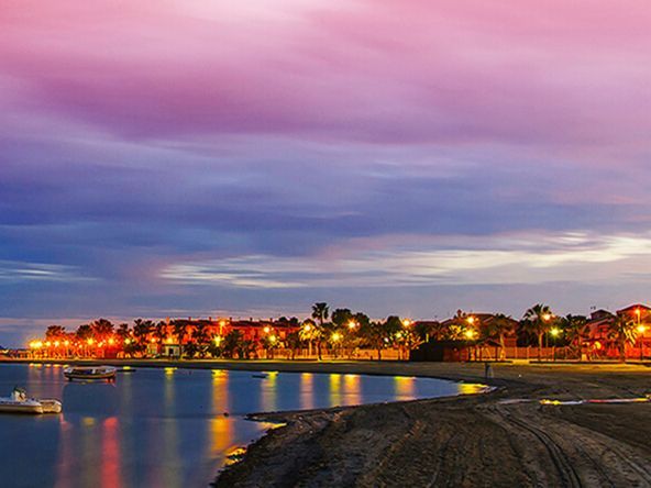A sunset over a body of water with a city in the background.