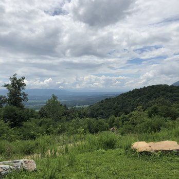 Overlooking a valley with green hills under a cloudy sky.