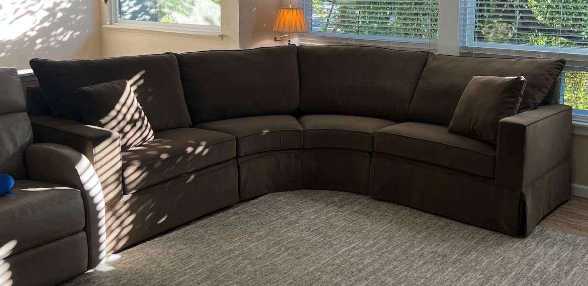 A brown sectional couch is sitting in a living room next to a window.