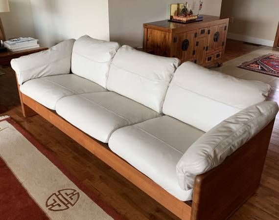 A wooden couch with white cushions in a living room