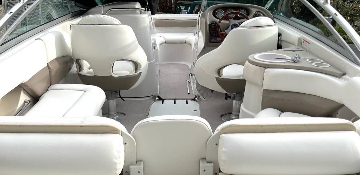 The inside of a boat with white seats and a table.