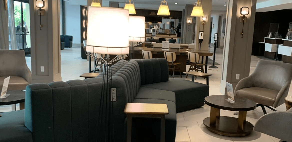 A hotel lobby with a couch , chairs , tables and lamps.