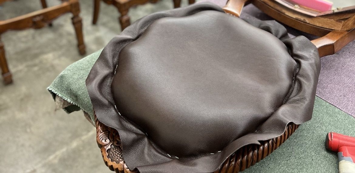A black cushion is sitting on top of a wooden chair.