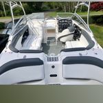 A white boat with black seats is parked in a yard.