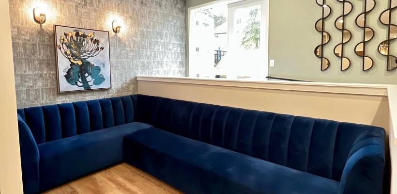 A waiting room with a blue couch and a painting on the wall.