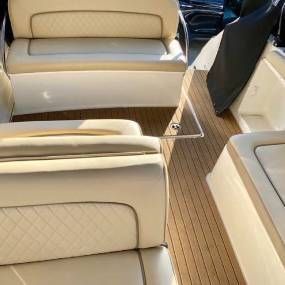 The inside of a boat with wooden floors and white seats.