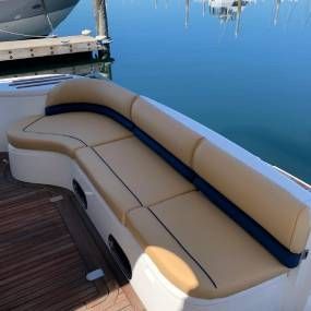 A boat with a couch on the back of it is docked in the water.