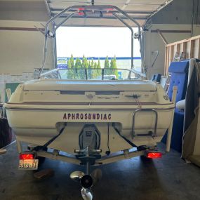A white boat with the name aphrosundiac on the back is parked in a garage
