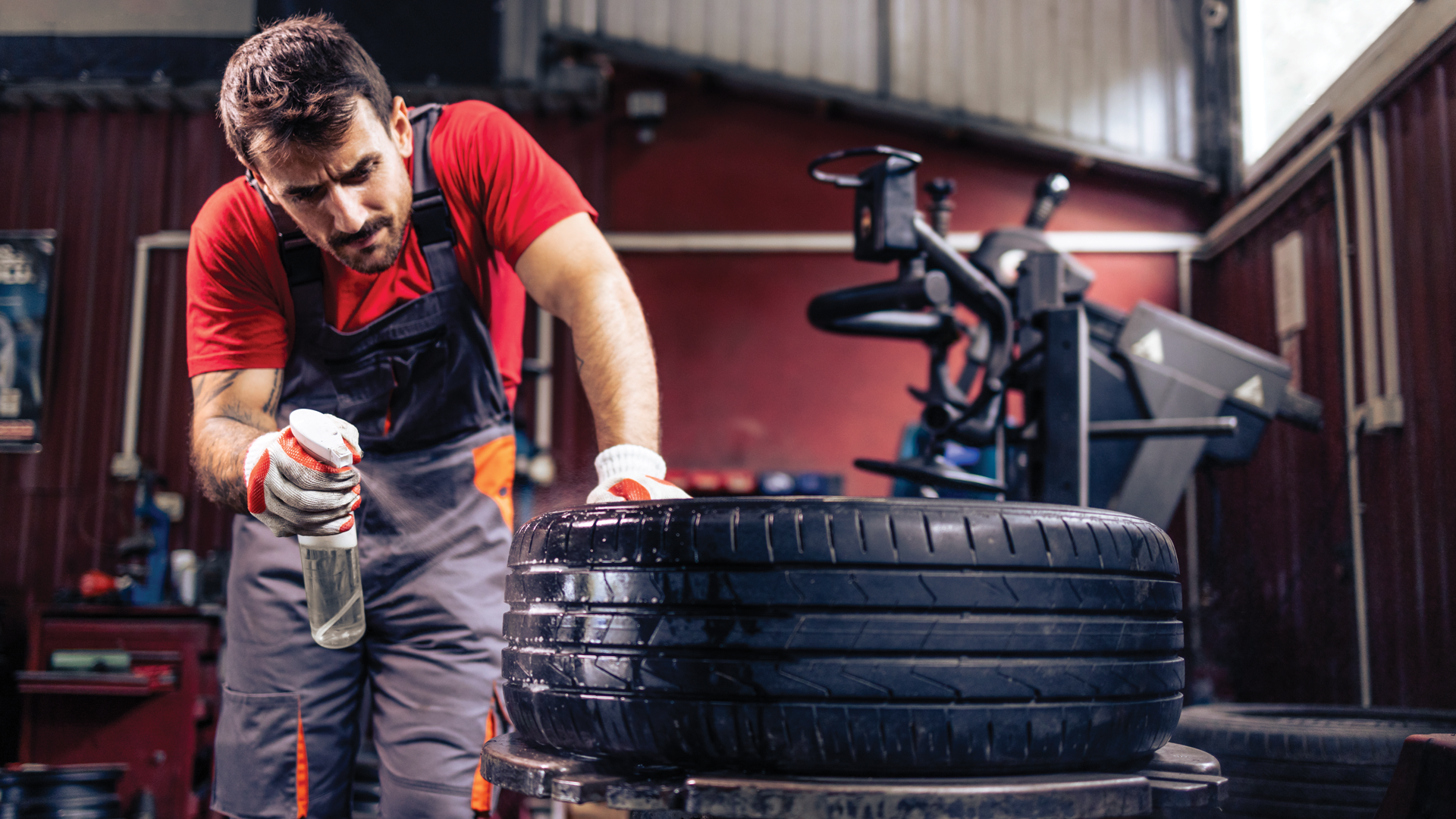A man is cleaning a tire in a garage.
