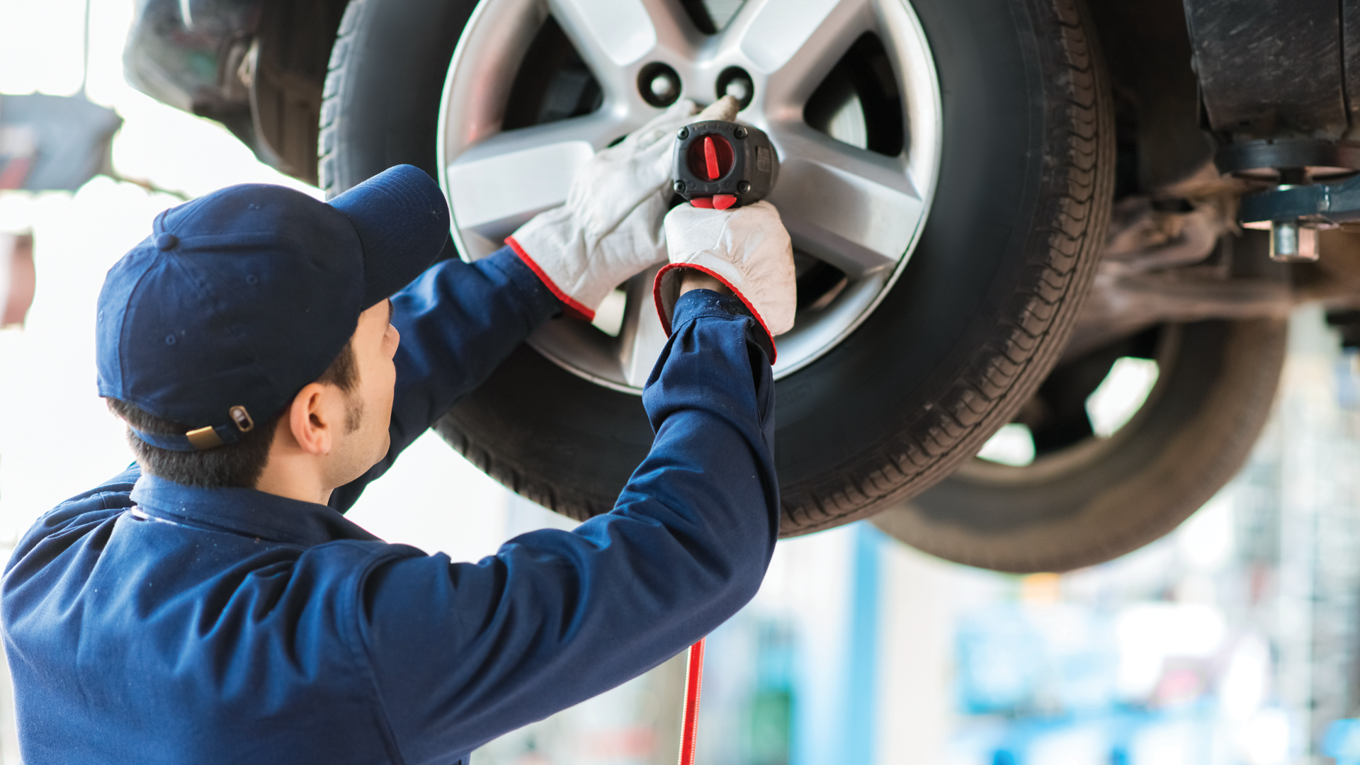 A man is changing a tire on a car in a garage.