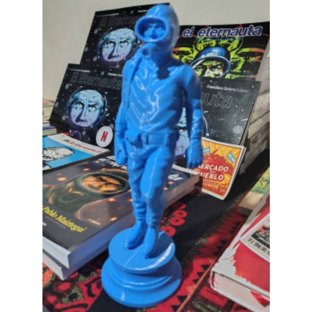 Una estatua azul de un hombre con una máscara de gas está rodeada de libros.