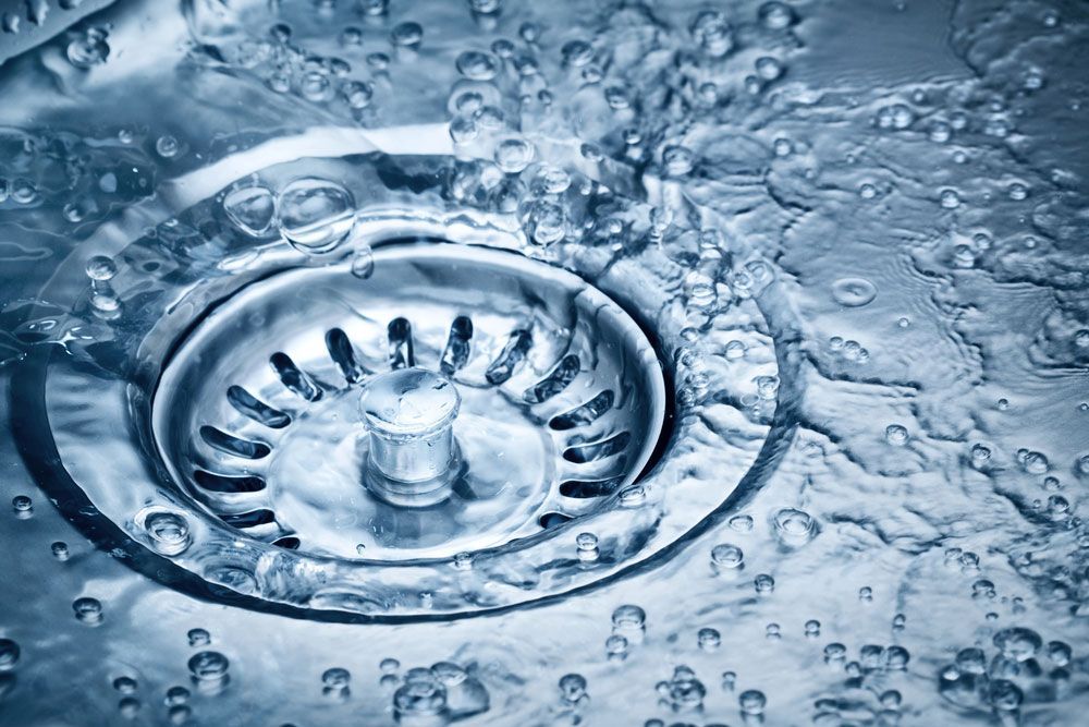 A close up of a sink drain with water coming out of it.