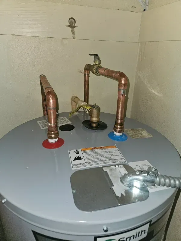Water heater with copper pipes, blue and red fittings.