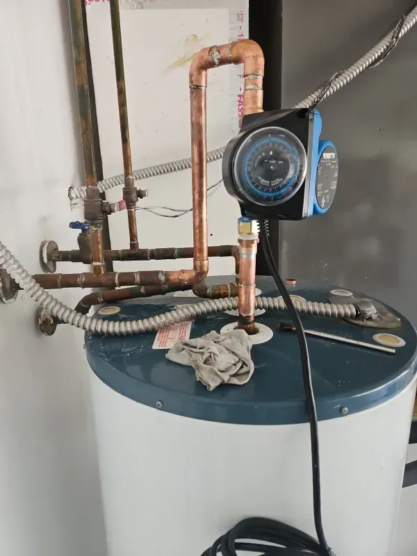Water heater with copper pipes and a pump attached.