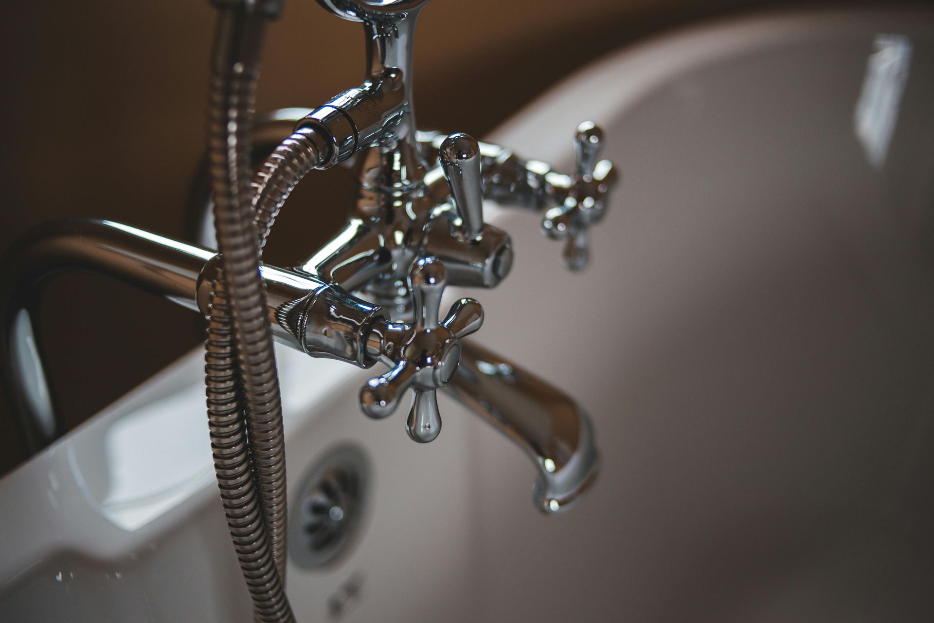 Chrome bathtub fixtures with hand shower, close-up shot.