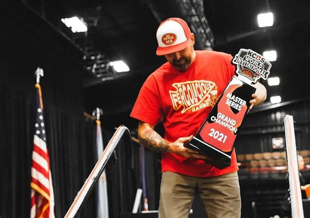 A man in a red shirt is holding a trophy in his hands.