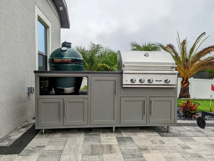 A large grill is sitting on top of a patio next to a house.