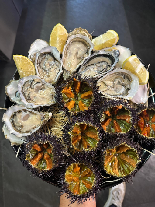 Ostriche su ghiaccio disposte attorno a spicchi di limone e guarnizione di frutti di mare scuri