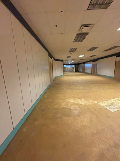 A long empty hallway with white walls and a brown floor.