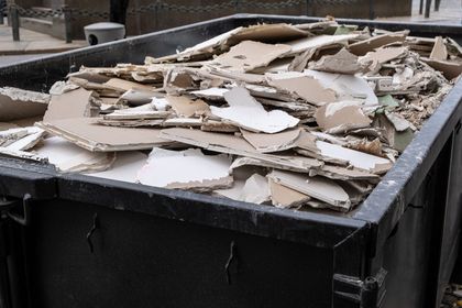 A dumpster filled with a lot of cardboard pieces
