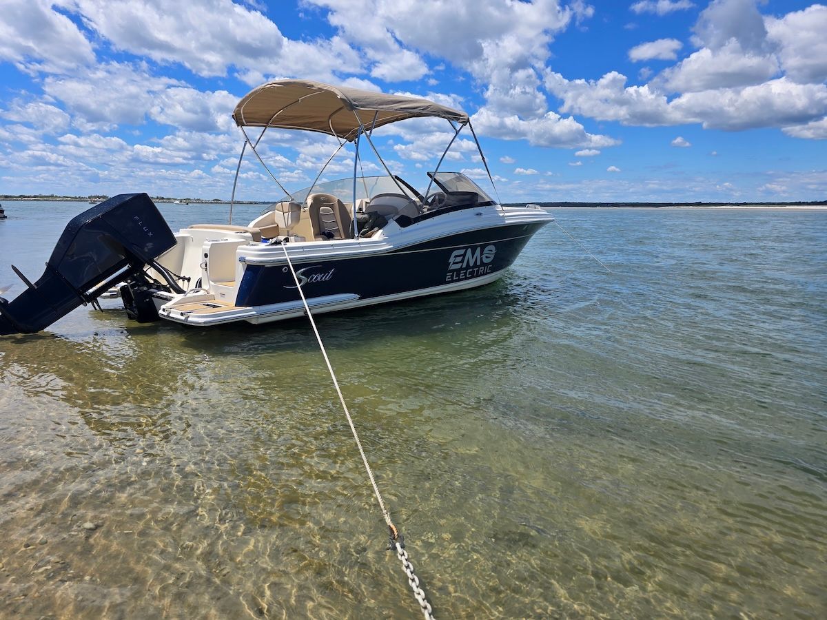 Blue Scout 215 Dorado with bimini top anchored at beach