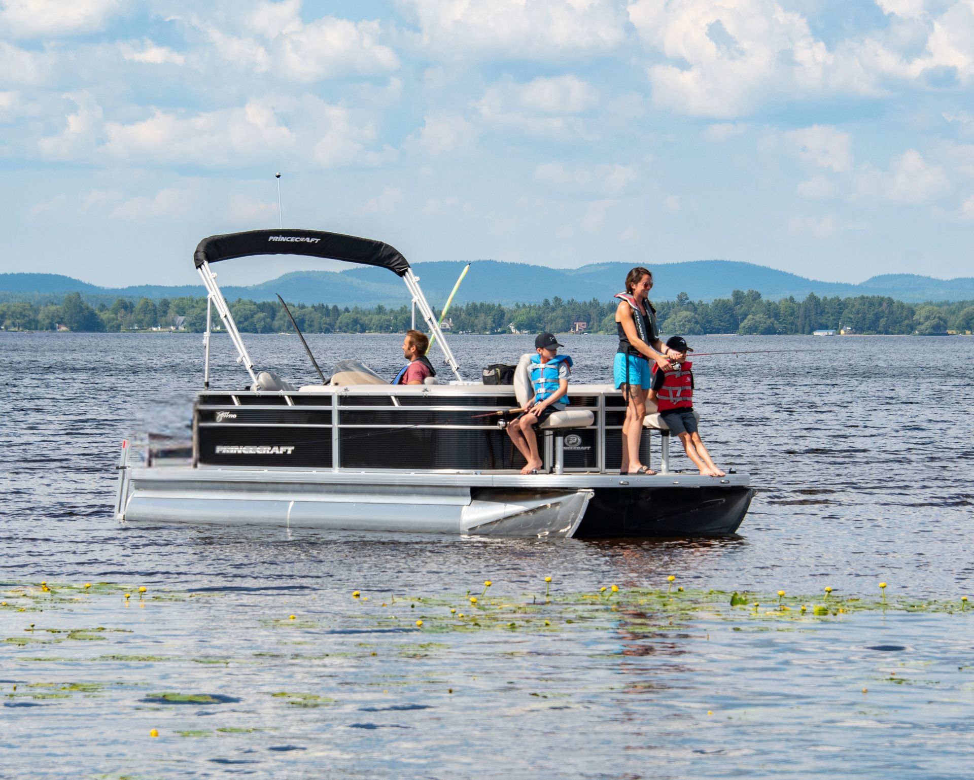 A man and woman are riding a pontoon boat on a lake.