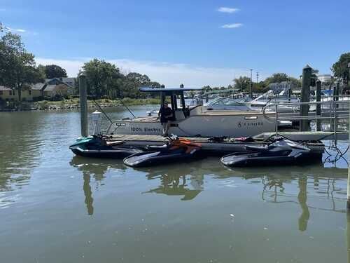 A couple of jet skis are docked next to a boat in the water.