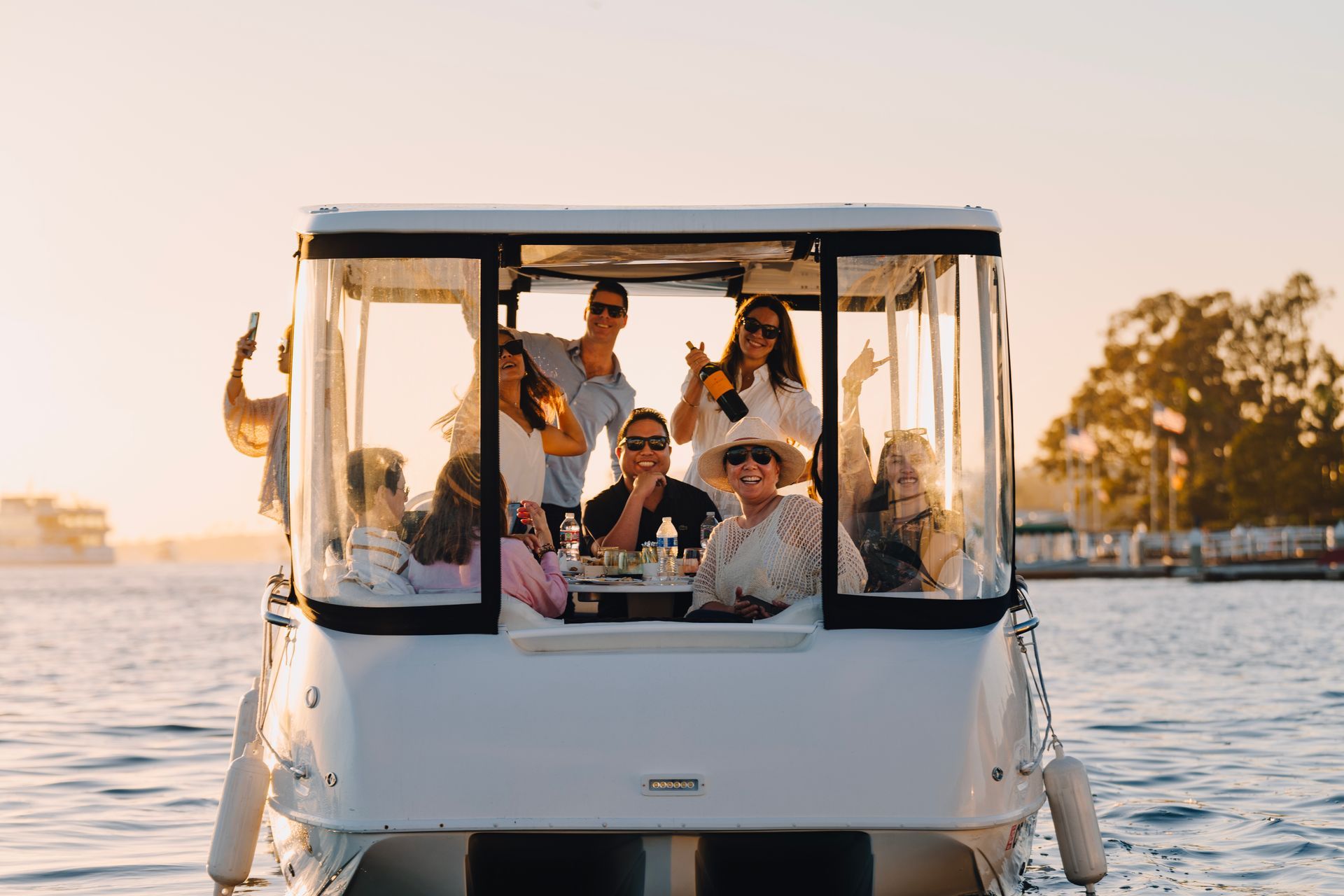 Friends smiling on electracraft boat cocktail cruiser at sunset