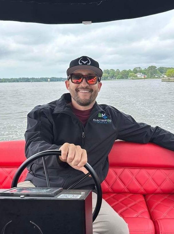 A man is sitting on a boat holding a steering wheel.