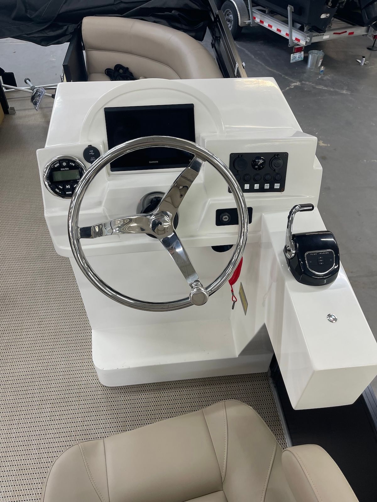 Helm station on a pontoon boat showing steering wheel, throttle, nav screen and movable captain chair