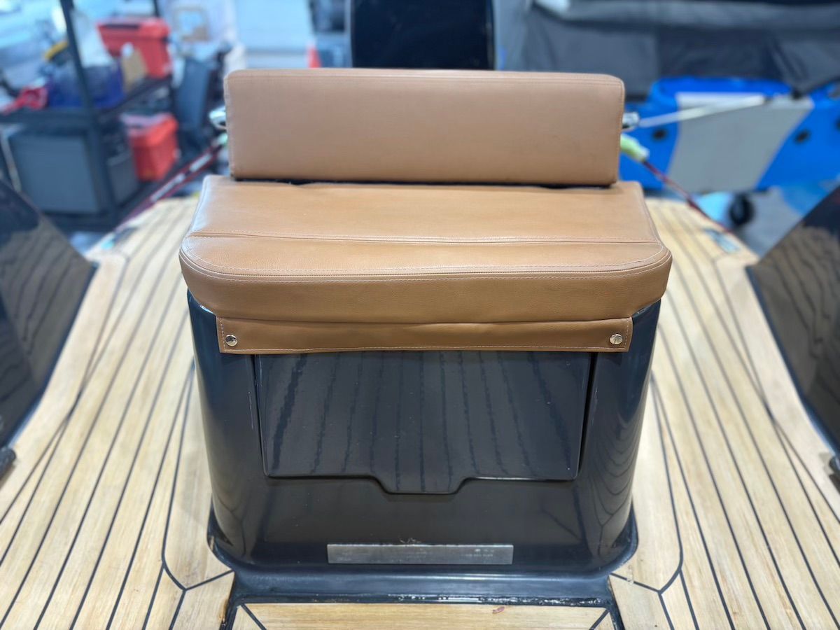 Seating bench at end of boat brown cushion and two buttons on either side to enforce cushion on seat; teak flooring in backgroun