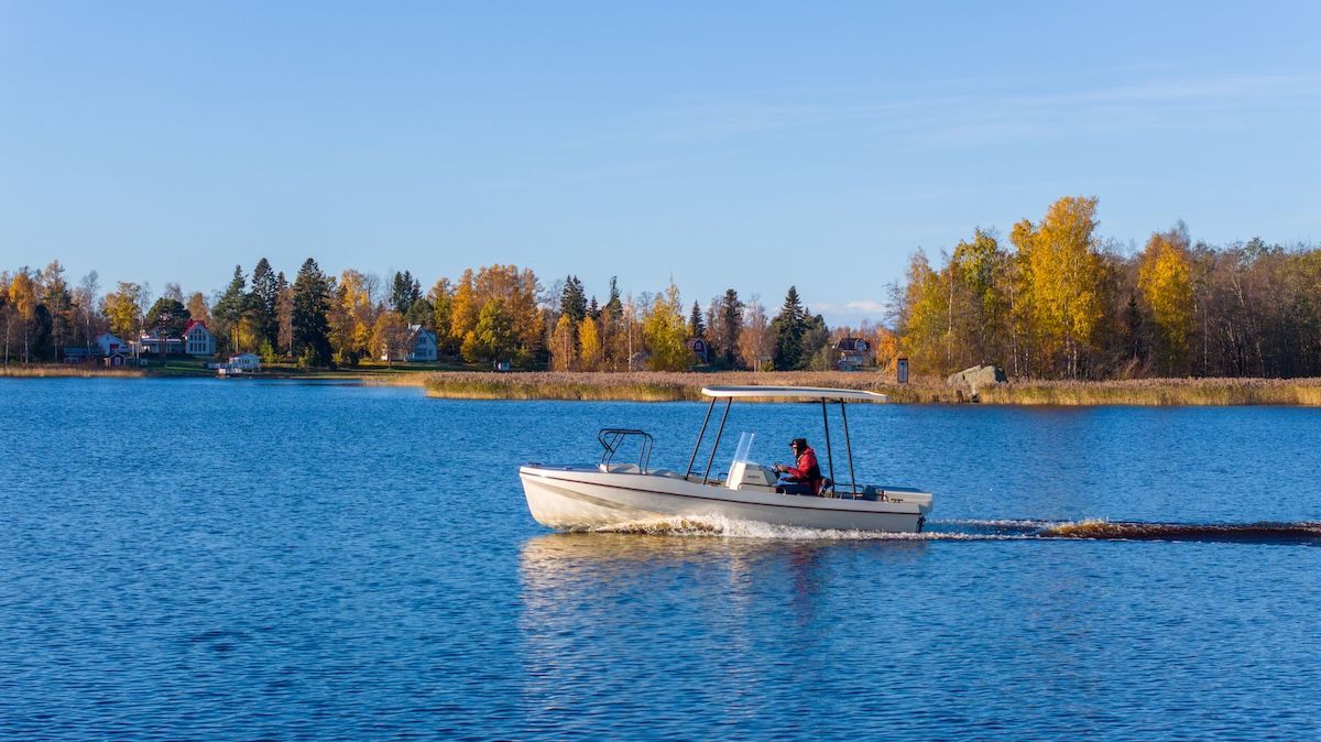 single rider in center console solar electric boat and day cruiser fall foilage in background