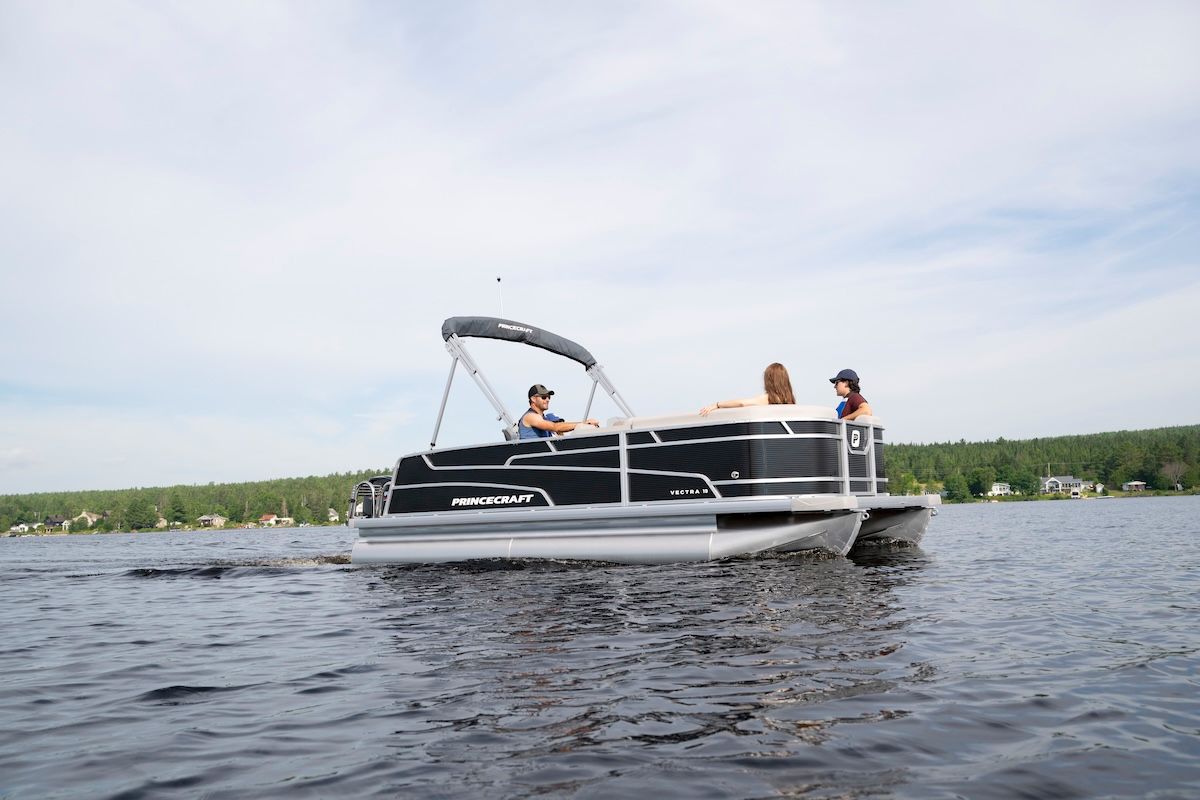A man and woman are riding a pontoon boat on a lake.