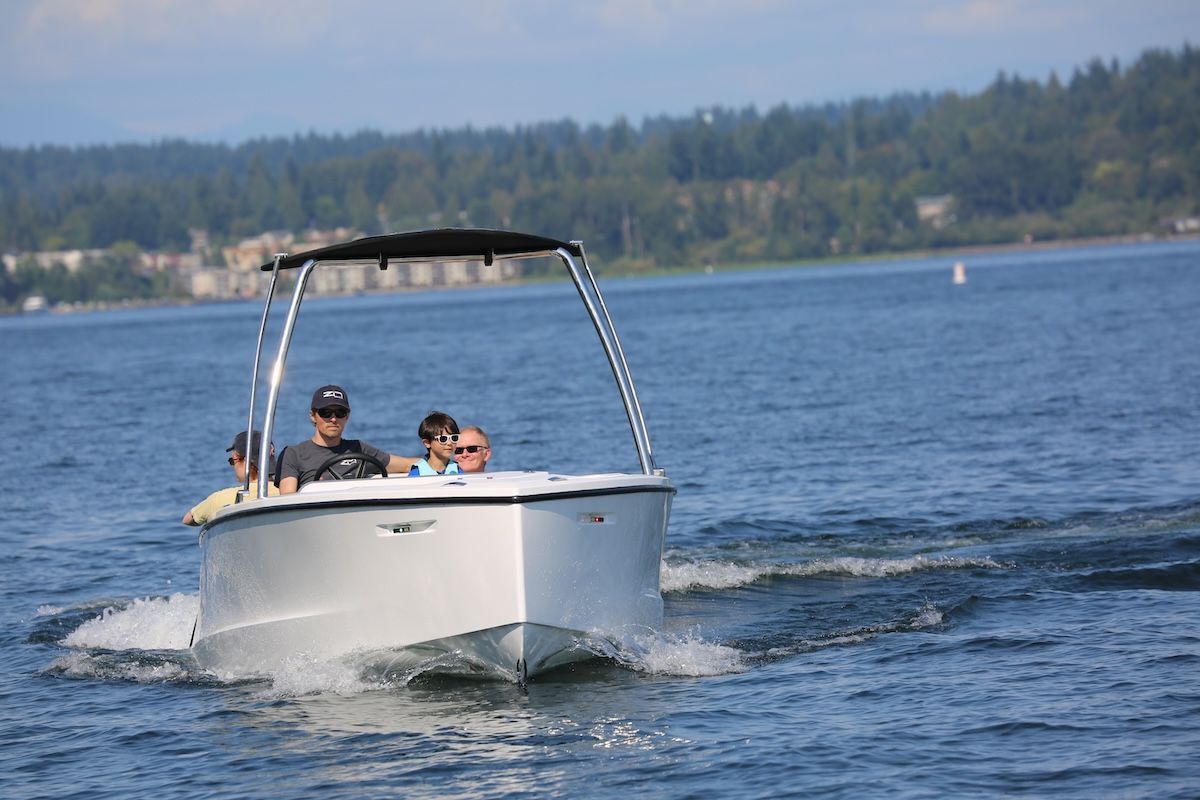People enjoying time together on boat center console two in back one in captain and one up front