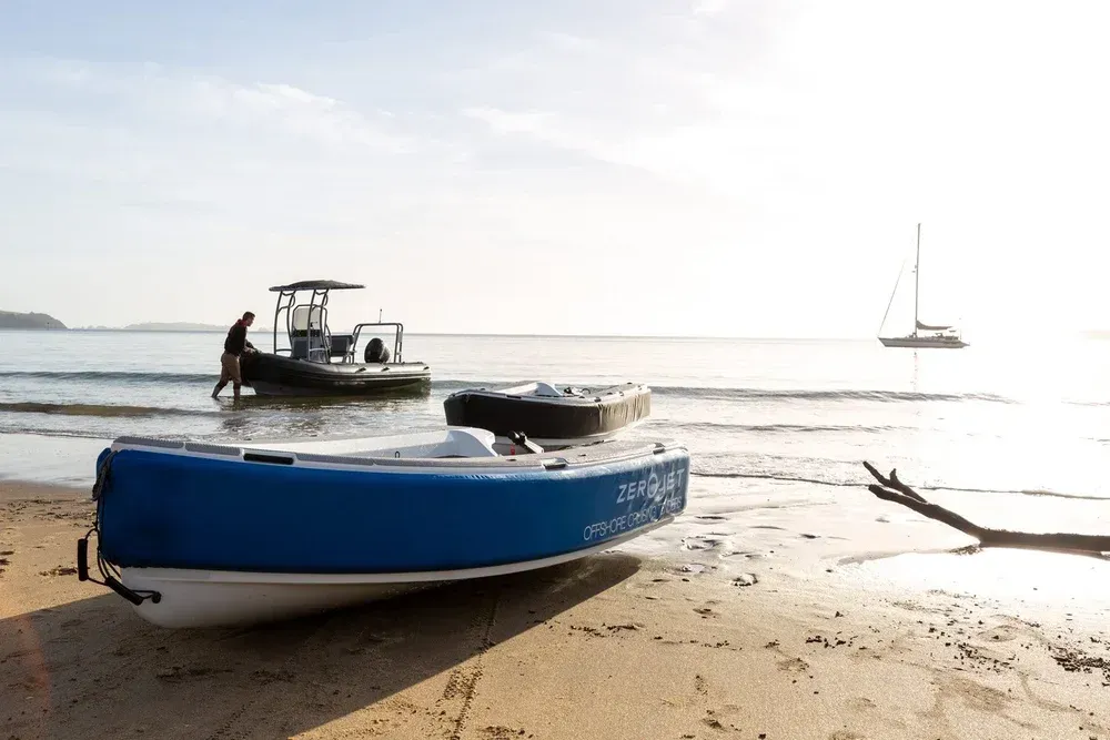 Zerojet OCT beached with another boat in the background and a sailboat in the water