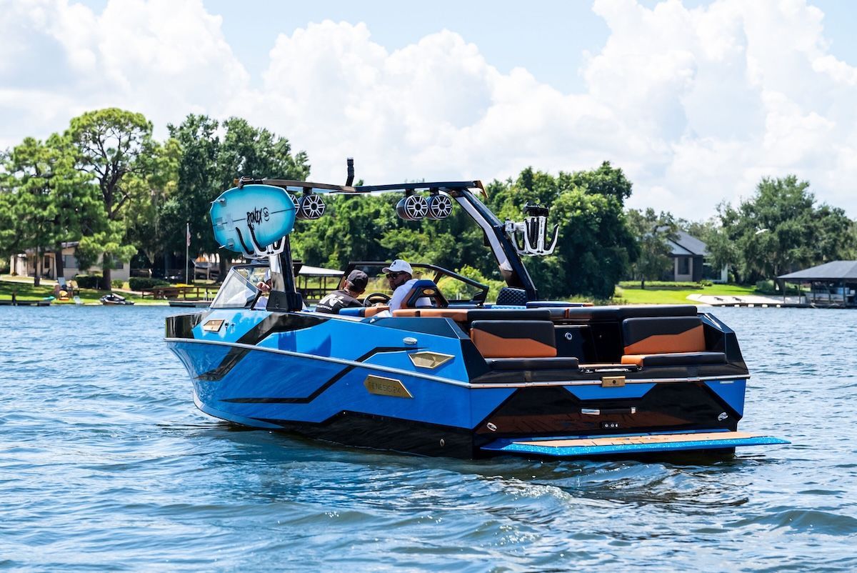 transom of hybrid wake surfing boat bright blue surf board rack in use still in water