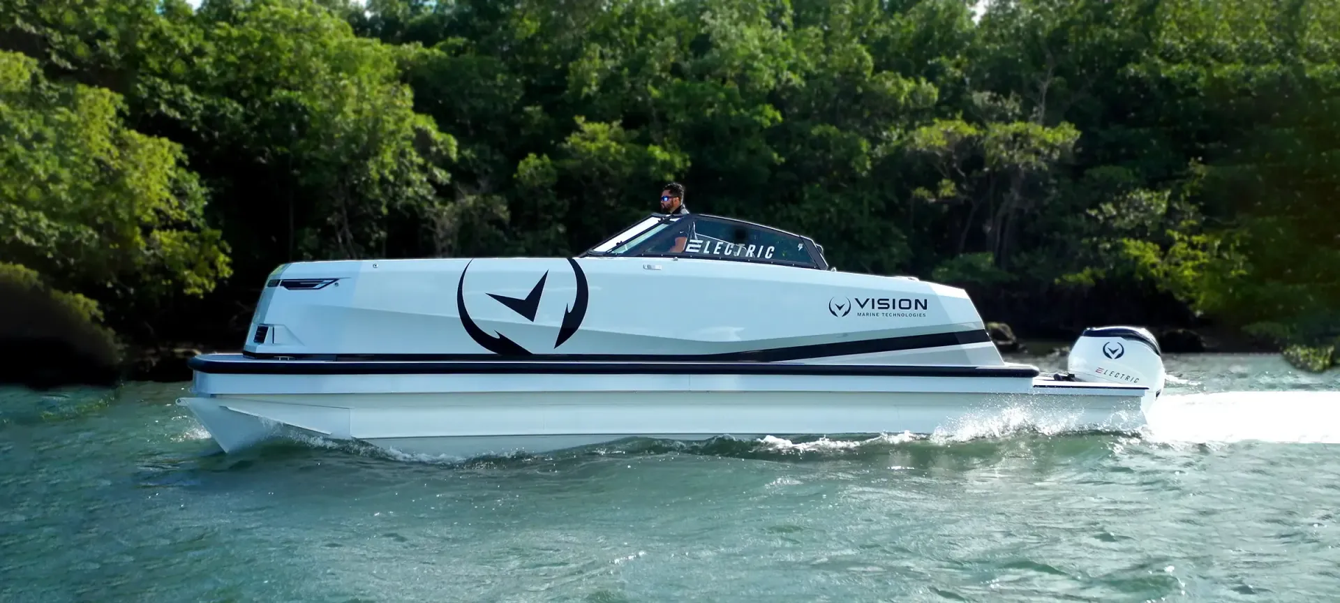 Spectr pontoon tri hull from Vision Marine green trees in background blue water big Vision Marine logo on side of boat