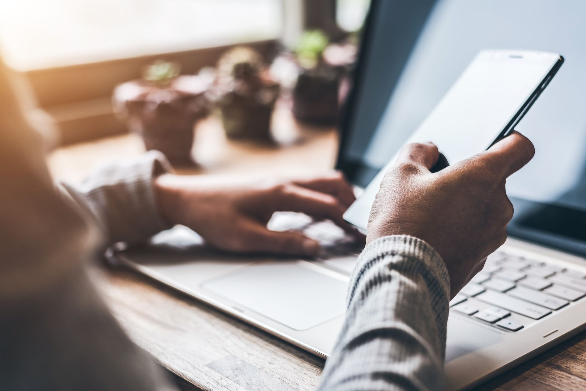 A person is using a laptop and a cell phone at the same time.