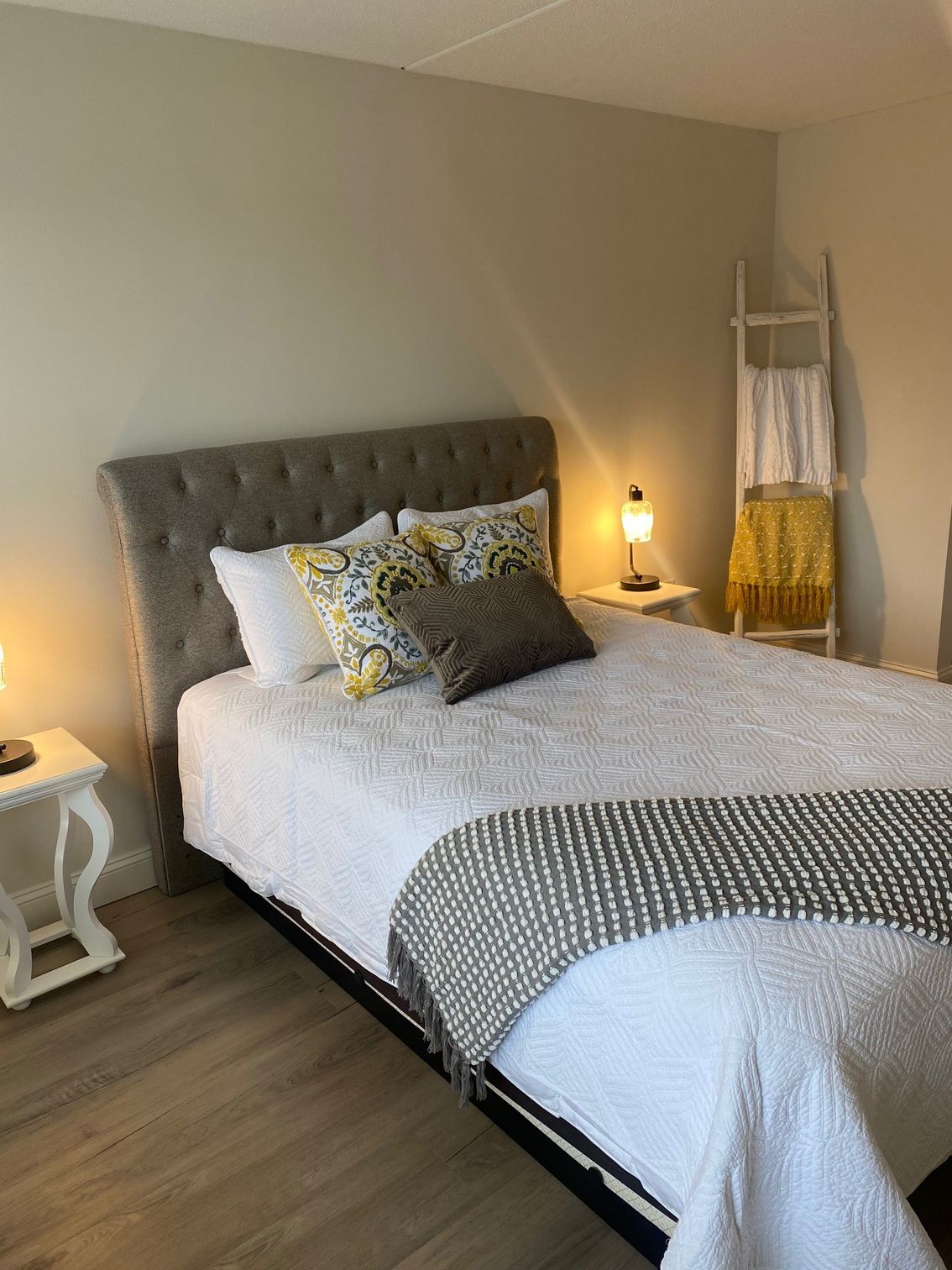 A bedroom with a bed , nightstand , lamp and ladder.