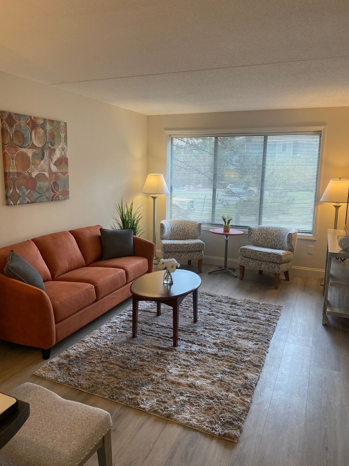 A living room with a couch , chairs , coffee table and rug.