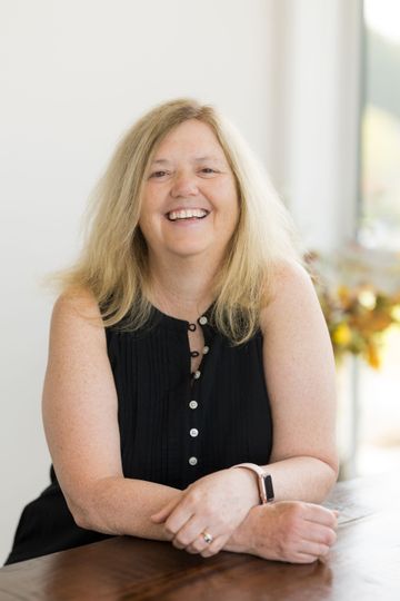 A woman is smiling in front of a calendar on the wall