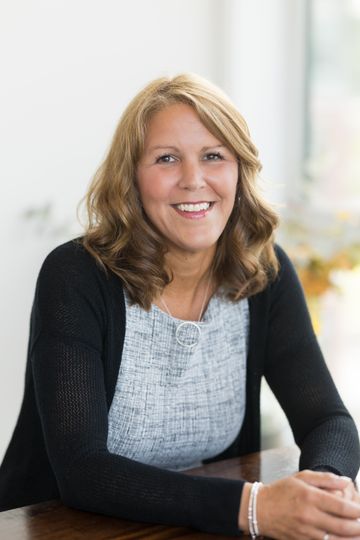 A woman is sitting in an office chair and smiling.