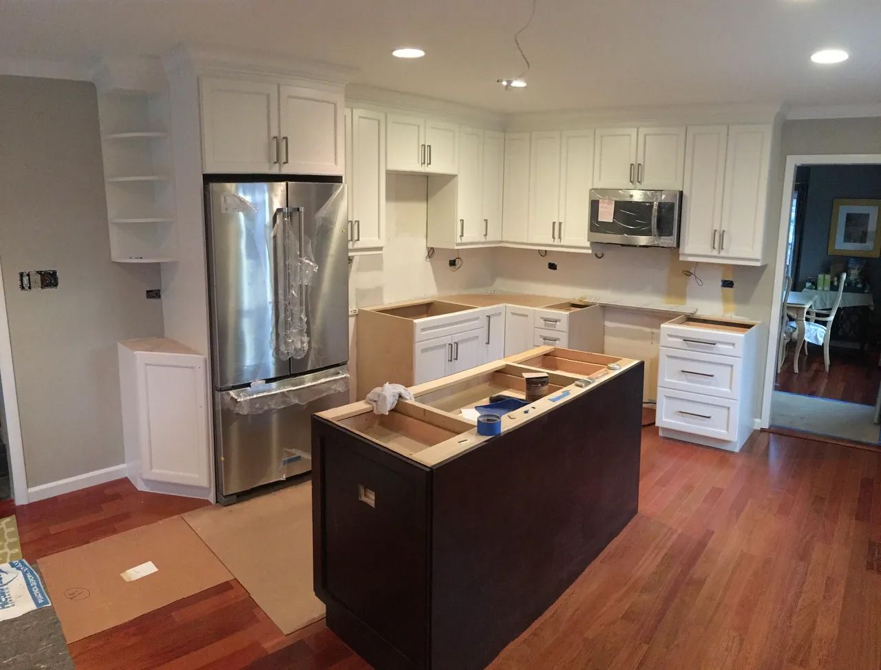 A kitchen with white cabinets and stainless steel appliances is being remodeled.