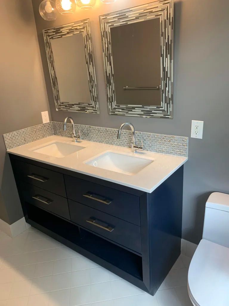 A bathroom with two sinks , two mirrors and a toilet.