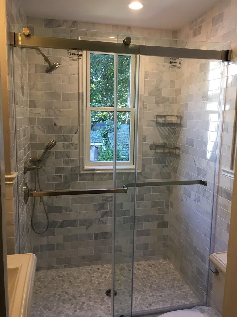 A bathroom with a sliding glass shower door and a window.