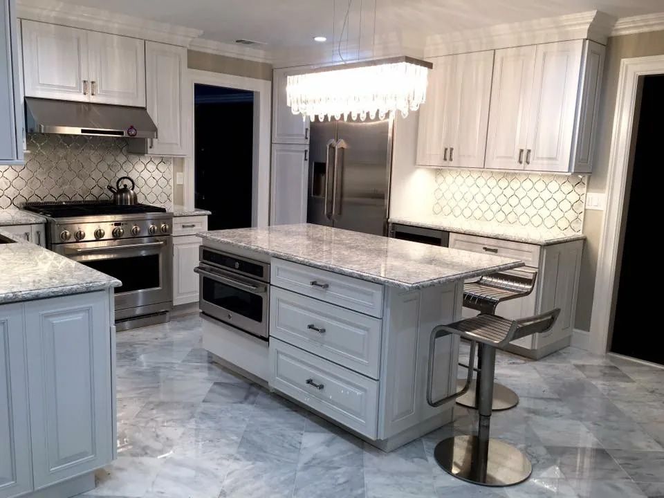 A kitchen with white cabinets , stainless steel appliances and a large island.
