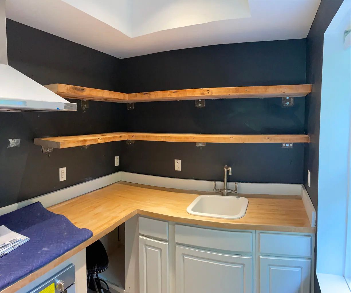 A kitchen with wooden shelves and a sink